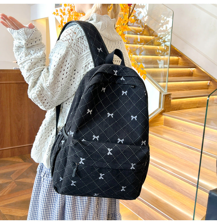 Side view of the black quilted bow-print backpack being worn