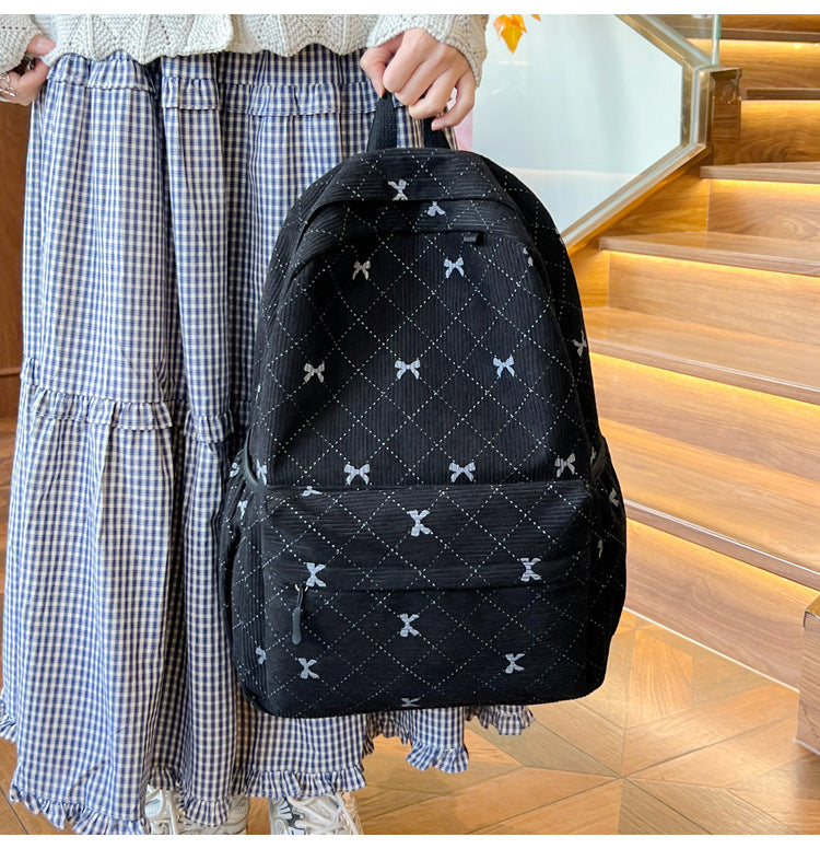 Front view of the black quilted bow-print backpack