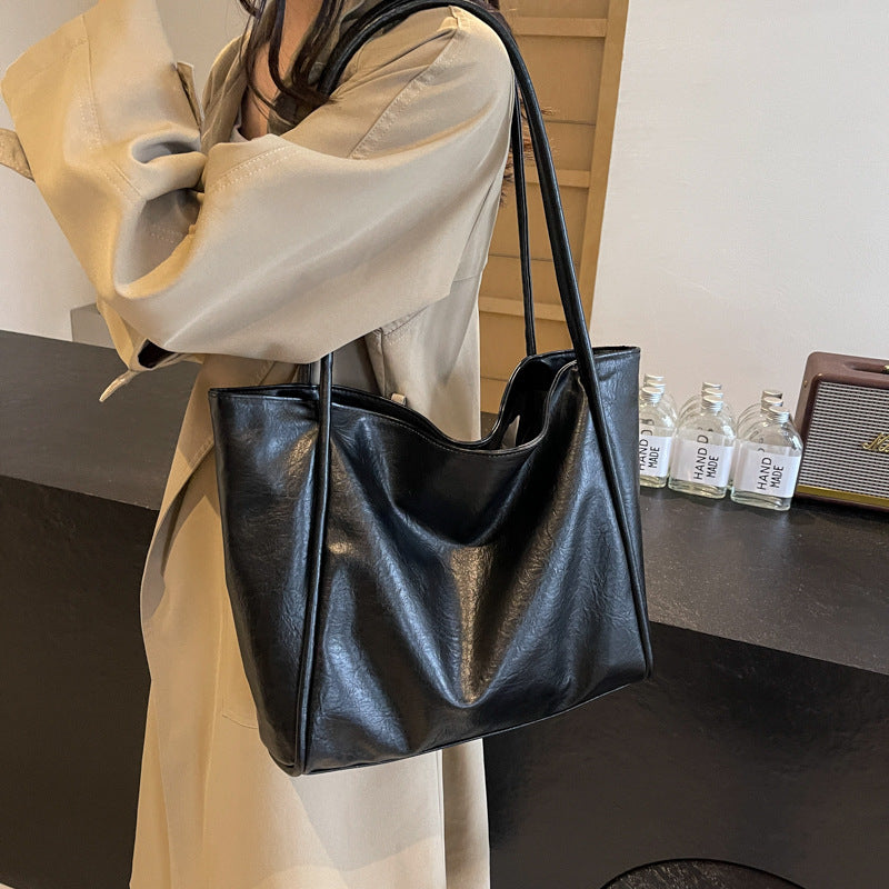 Black soft PU leather shoulder tote bag carried by a model