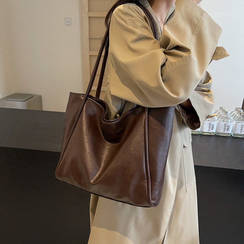 Brown soft PU leather shoulder tote bag carried by a model