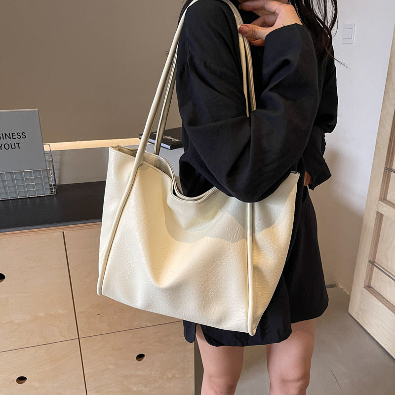 Milky white soft PU leather shoulder tote bag carried by a model